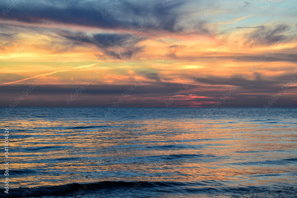 Baltic sea. Colourful sunset at the end of the day with clouds reflection on the water.