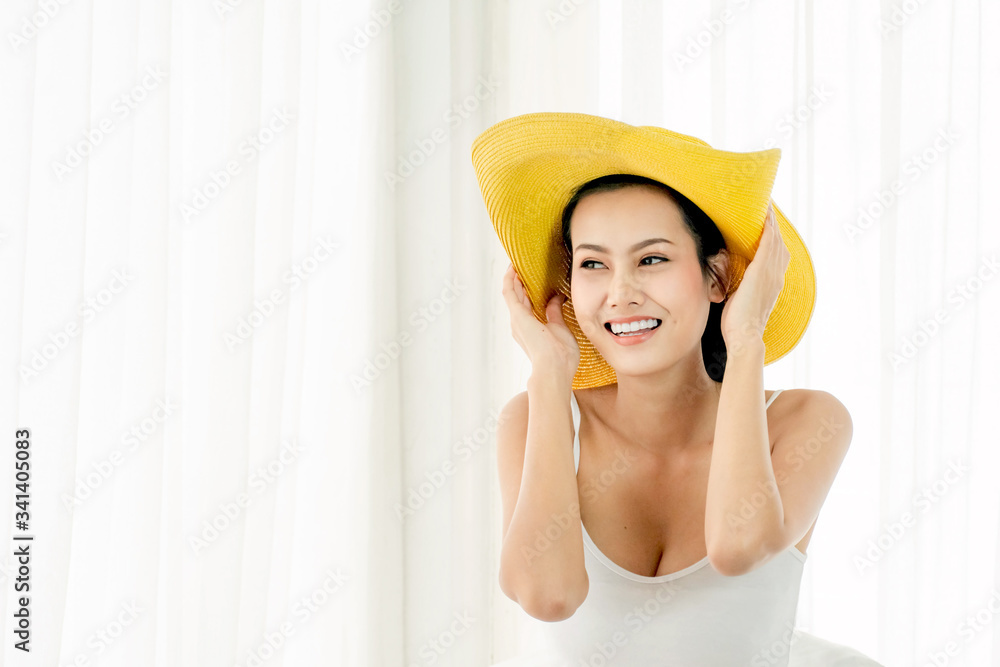 Smiling beautiful asian woman wearing the yellow hat and thinking about her dream trip. Happy young woman packing travel luggage and plan the trip. Smiling beautiful asian woman wearing the yellow hat and thinking about her dream trip. Happy young woman packing travel luggage and plan the trip.