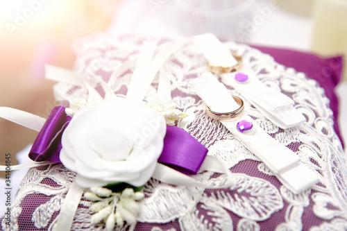 wedding rings on satin cushion with lace and floral decor. Selective focus. Disfocused background