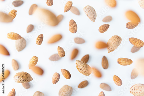 Shelled almond nuts flying above white background, levitation effect