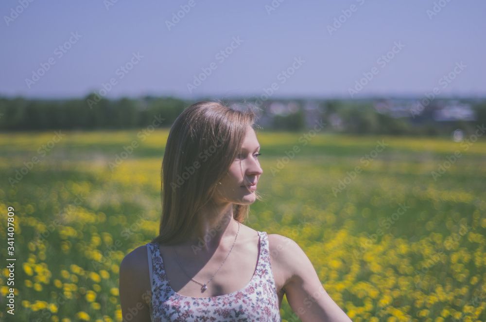 Woman in dress posing in summer on a field with yellow dandelions Woman in dress posing in summer on a field with yellow dandelions