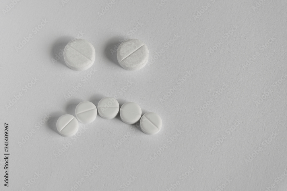 concept of bad medicine. sad face made up of pills on blue backgroud concept of bad medicine. sad face made up of pills on blue backgroud