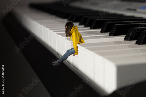 The girl is sitting on the piano keys. Art music photo