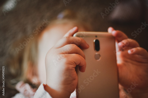 Beautiful little girl watching cartoons on a smartphone. Video communication. Online call to friends. The distance of friends. Teaching children online. A child plays on a smartphone.