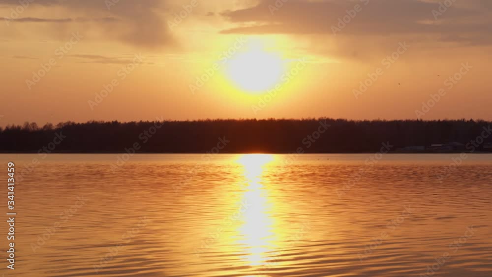 Sun setting over tranquil lake and forest Sun setting over tranquil lake and forest