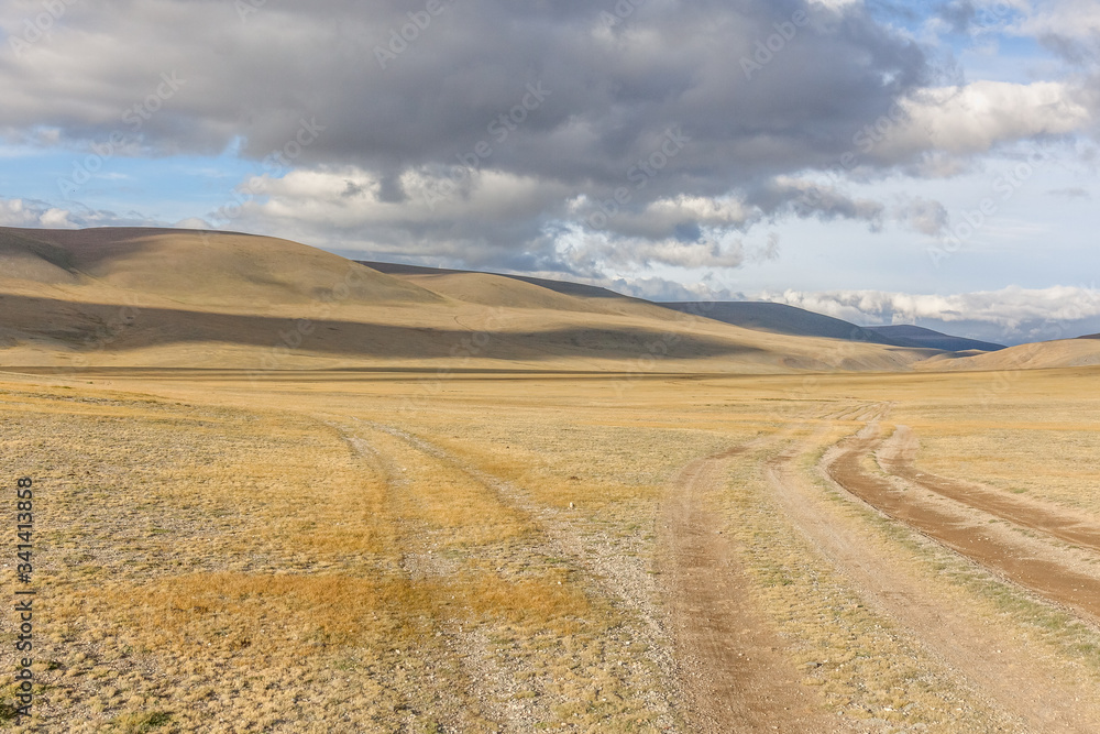 Mongolia landscape. Winding dirt road through lush rolling hills of Central Mongolian steppe. Mongolian Altai