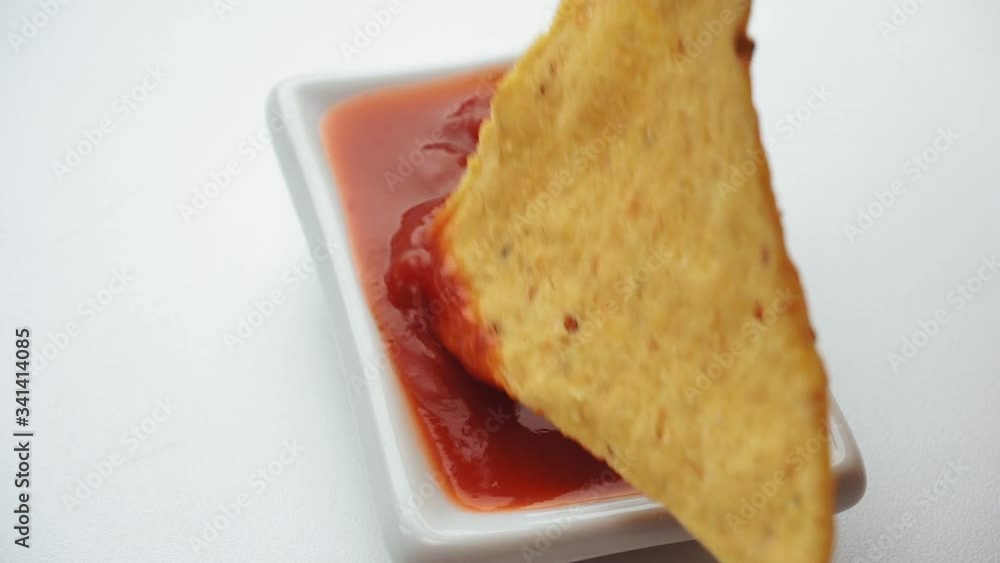 Close up dipping tortilla chips in salsa sauce. selective focus corn chips Close up dipping tortilla chips in salsa sauce. selective focus corn chips