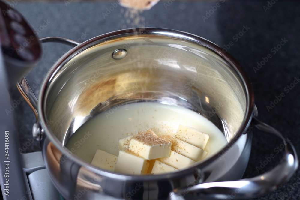 Pouring brown sugar into condensed milk with diced butter. Making Boston Banoffee Pie. Pouring brown sugar into condensed milk with diced butter. Making Boston Banoffee Pie.