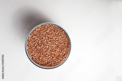 organic buckwheat in a transparent glass jar on top on a white background