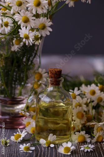 Daisies, chamomile flowers and chamomile oil in bottles on wooden background