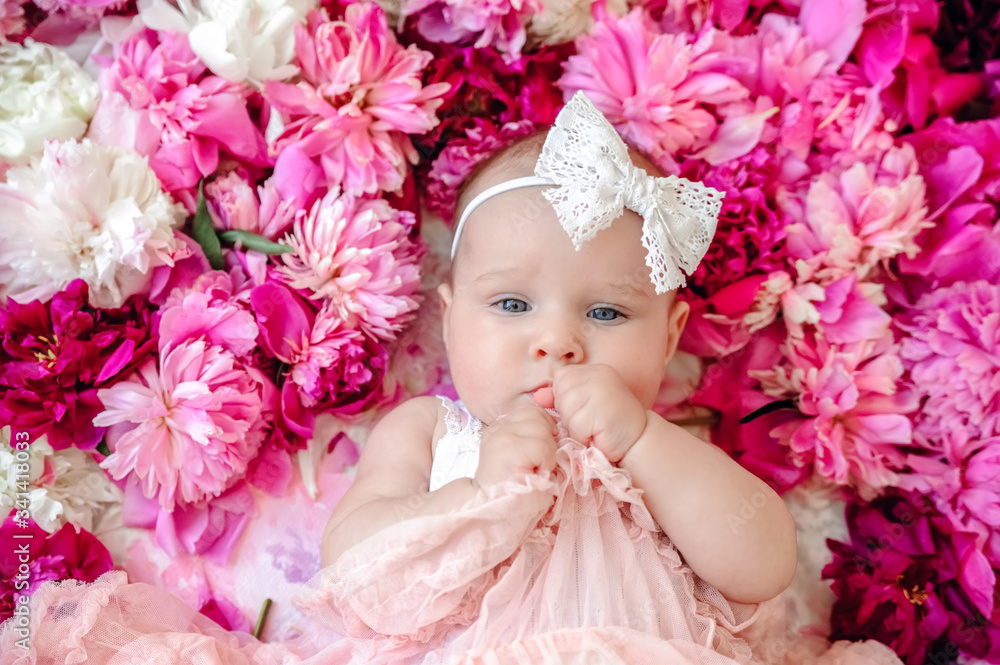 Cheerful smiling little girl on a background with pink peonies. Cute baby girl wearing wreath. Smiling girl on pink background with wreath of peonies on her head. Greeting card mother's day. Cheerful smiling little girl on a background with pink peonies. Cute baby girl wearing wreath. Smiling girl on pink background with wreath of peonies on her head. Greeting card mother's day.