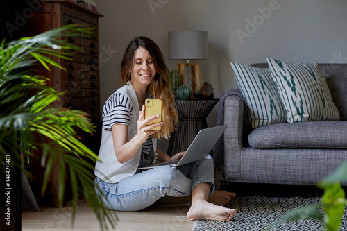 Mujer joven trabajando en casa con su ordenador y su teléfono movil