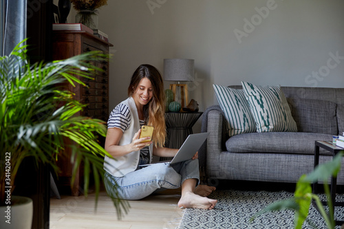 Mujer joven trabajando en casa con su ordenador y su teléfono movil