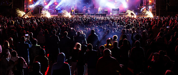 silhouettes of concert crowd in front of bright stage lights.