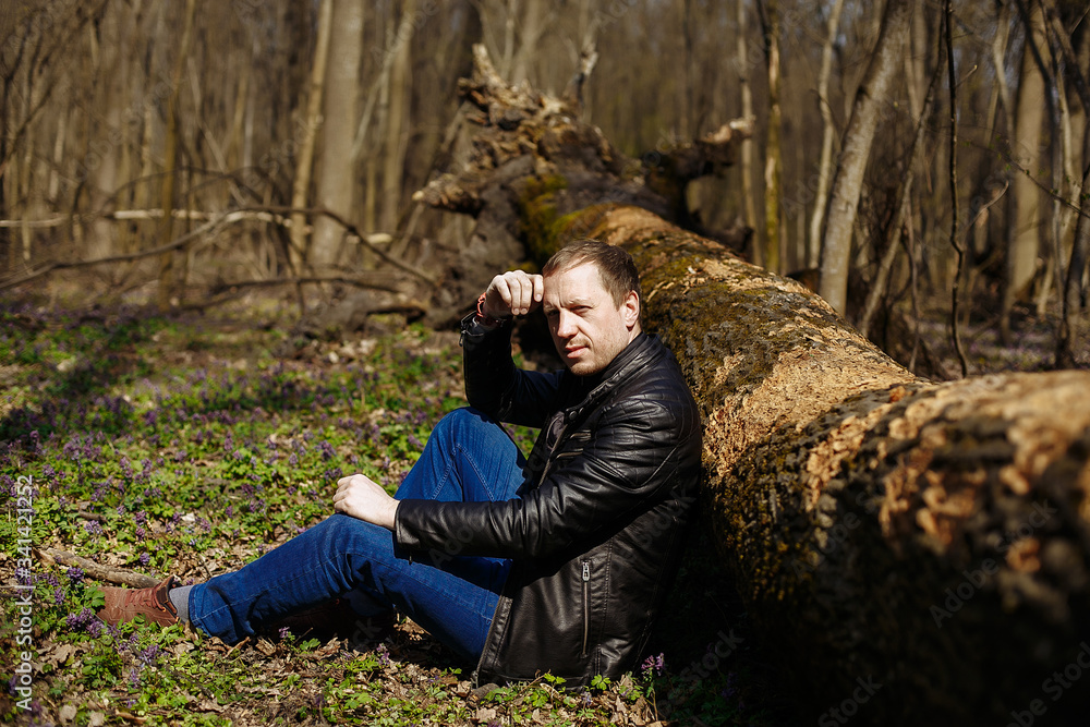 Obraz premium a man sits under a fallen tree in the forest