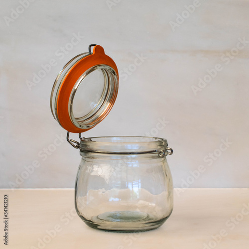 An empty Kilmer round clip top glass storage jar with an orange rubber seal.  The jar lid is open and the objects is isolated against a plain white background  photo