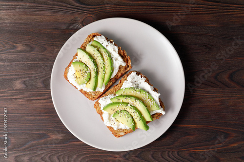 Variation of healthy toasts with avocado cream cheese and whole wheat rye bread on a plate. Delicious snacks and avocado sandwiches. Food composition, tasty Italian meal. Top view