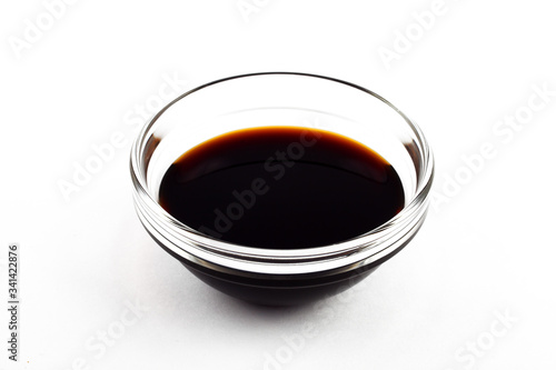 Soy sauce in a glass saucepan on a white plate, isolate