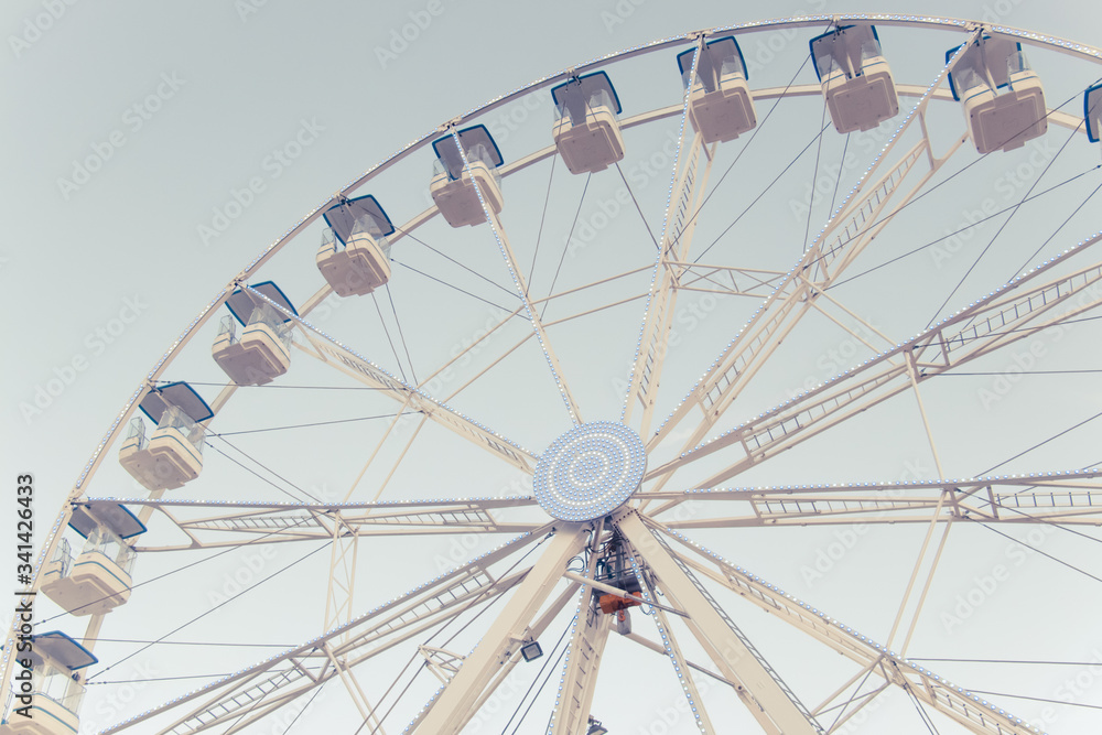 A part of ferris and blue sky. Beatiful background with ferris. Blue, light, white, sky, ferris wheel. Ferris wheel and piece sunlight. Vintage style. A part of ferris and blue sky. Beatiful background with ferris. Blue, light, white, sky, ferris wheel. Ferris wheel and piece sunlight. Vintage style.