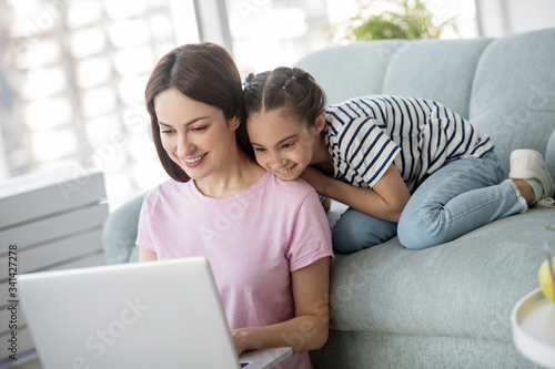 Mom with daughter seeing interesting things in a laptop.
