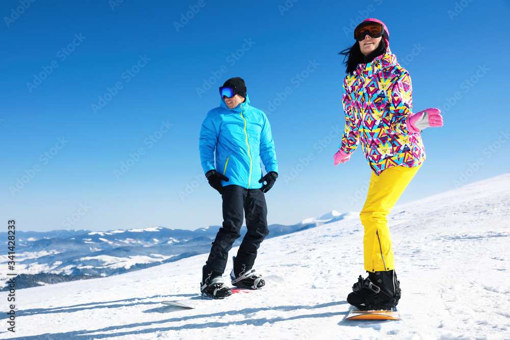 Couple snowboarding on snowy hill. Winter vacation