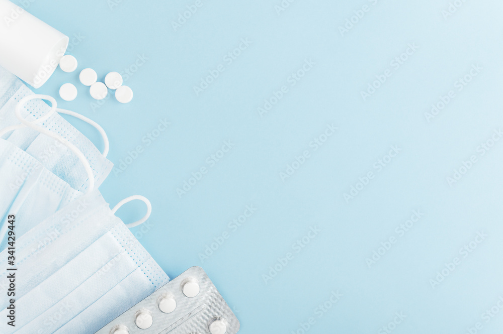 Personal hygiene products for human on backdrop. Medical protective mask and scattered tablets on light background. Mockup, copy space on right side. Health and hygiene concept. Isolated on blue - obrazy, fototapety, plakaty 