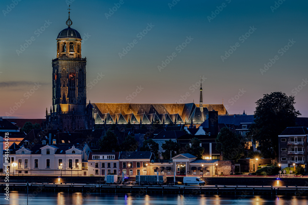Evening twilight long exposure of  the riverside promenade in Deventer, Netherlands, with IJssel river and St. Lebuinus Church.