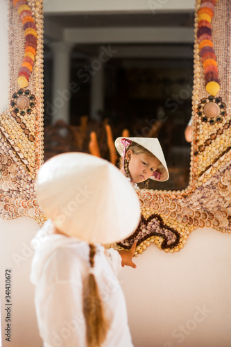 Little girl in Vietnameese touching traditional vietnameese mirror made with shells photo