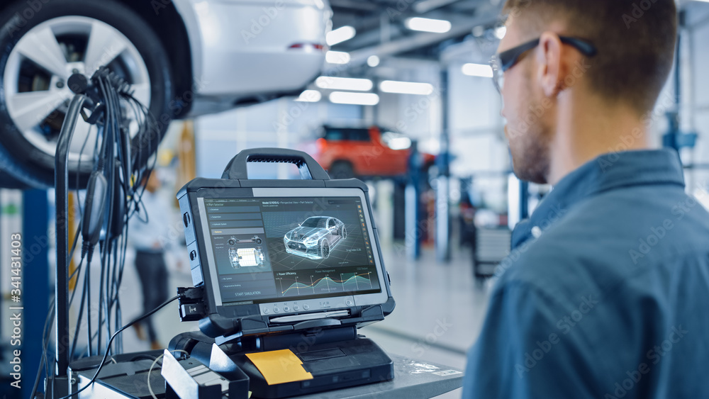 Car Service Manager or Mechanic is Running an Interactive Diagnostics Software on an Advanced Computer. Specialist Inspecting the Vehicle in Order to Find Broken Components and Errors in Data Logs. Car Service Manager or Mechanic is Running an Interactive Diagnostics Software on an Advanced Computer. Specialist Inspecting the Vehicle in Order to Find Broken Components and Errors in Data Logs.
