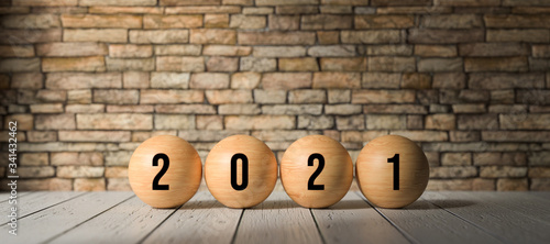 wooden spheres with number 2021 in front of a brick wall on wooden surface