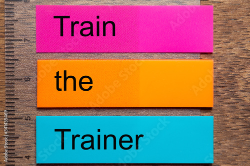 Wallpaper Mural The words Train the Trainer are written on three stickers . A dark wooden table as a background Torontodigital.ca