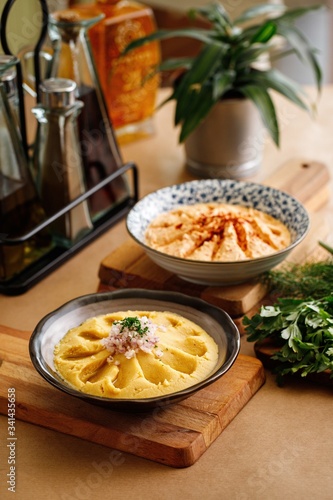 Tradition fava dip topped with onions, fine chopped parsley and olive oil. Tirokafteri dip made from greek feta cheese and yoghurt. Appetizer of greek cuisine plating photography on casual dine photo