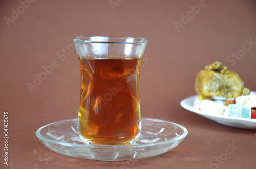 Tasty oriental sweets baklava, turkish delight on a plate on a dark black brown background and glasses of tea