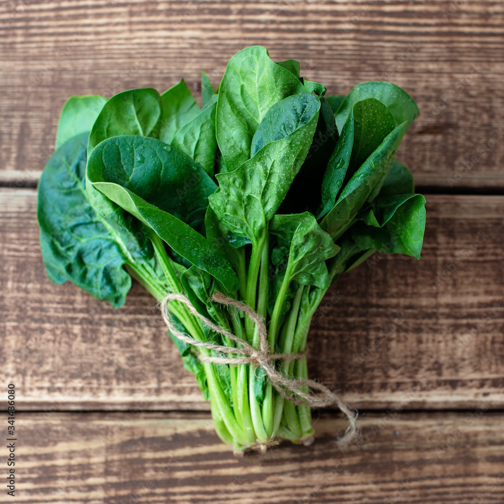 Fototapeta premium Clean food concept. Leaves of ripe juicy freshly picked organic spinach greens on a wooden background. Healthy detox spring-summer diet. Vegan Raw Food.