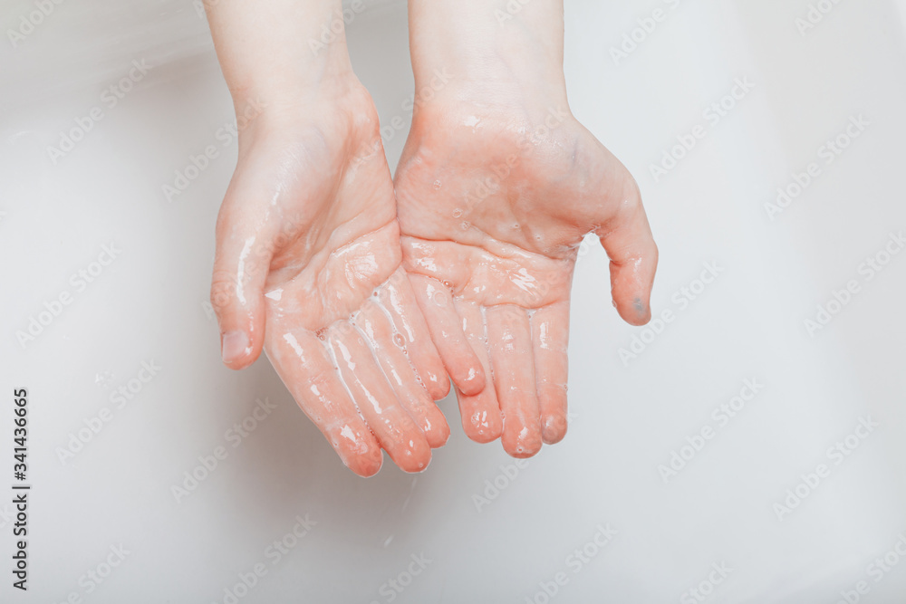 Fototapeta premium The child washes his hands thoroughly in the home bathroom.