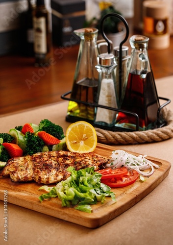 Mediterranean cuisine main course presentable plating on casual dine in background. Traditional greek chicken chop with fresh steamed vegetables photography for greek restaurant menu concept.