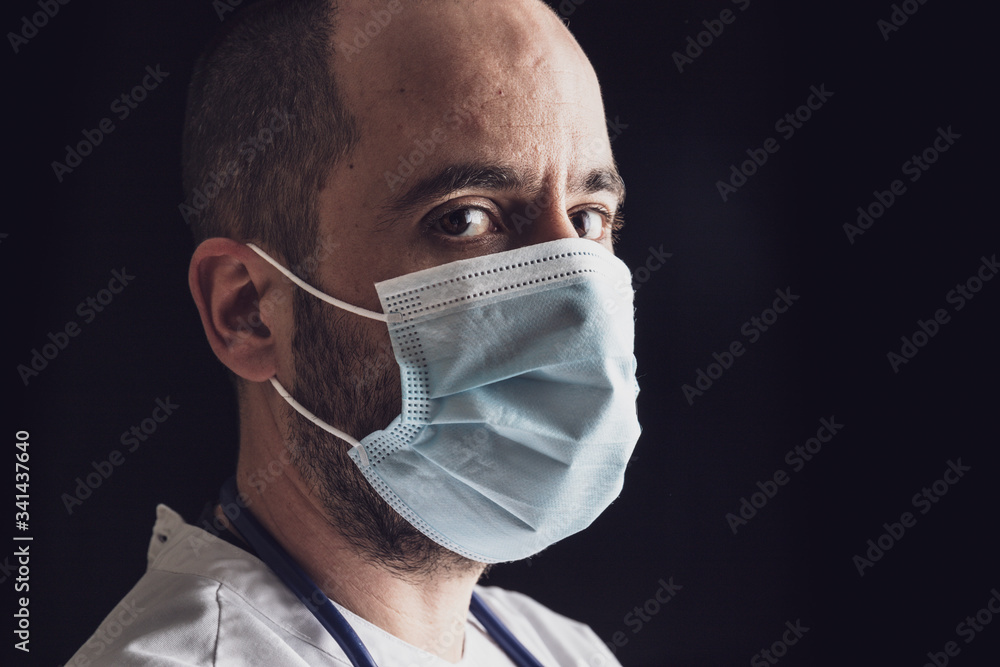 Close up portrait of a male doctor wearing a mask and stethoscope looks into the distance