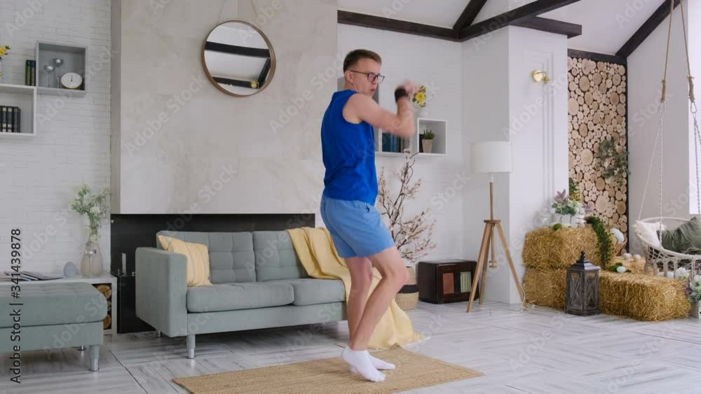 Cheerful energetic guy in sportswear and glasses dancing at home rejoicing at something Cheerful energetic guy in sportswear and glasses dancing at home rejoicing at something