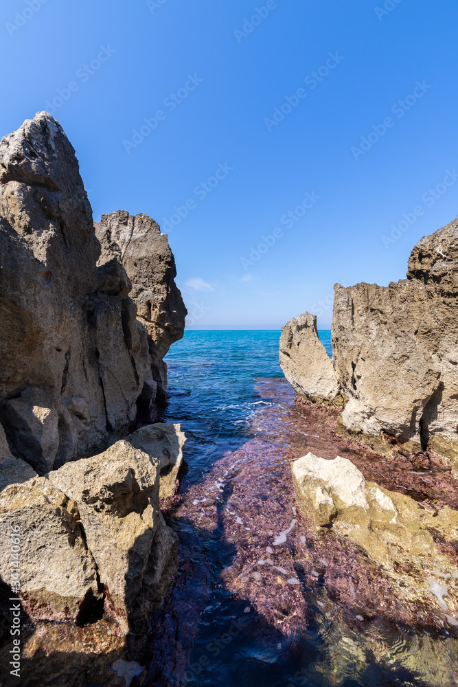 Idyllic view over the turquoise sea from the rocky coastline on a sunny day in Cefalu, Sicily, Italy.