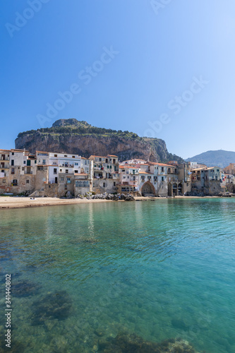 Fototapeta Naklejka Na Ścianę i Meble -  Idyllic view of turquoise sea and houses with Rocca di Cefalu rocky mountain in the background seen from historical old port of Cefalu, Sicily, Italy.