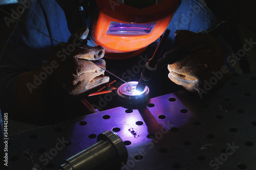 An industrial tig welder works in a workshop