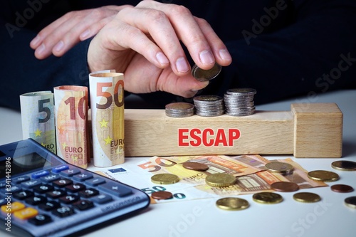 ESCAP. Mann stapelt Geld (Euro). Begriff ESCAP auf Baustein. Münzen, Scheine & Taschenrechner. Konzept für Business, Finanzen, Wirtschaft photo