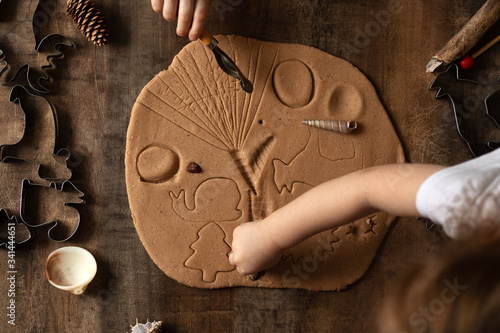 Children play with salt dough on the kitchen table. Hands mold clay with their own hands to create homemade zero-waist toys. Creative lesson with a test of natural products. 
