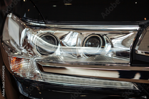 Closeup of a car headlight. Headlight of an expensive new car at a car dealership.