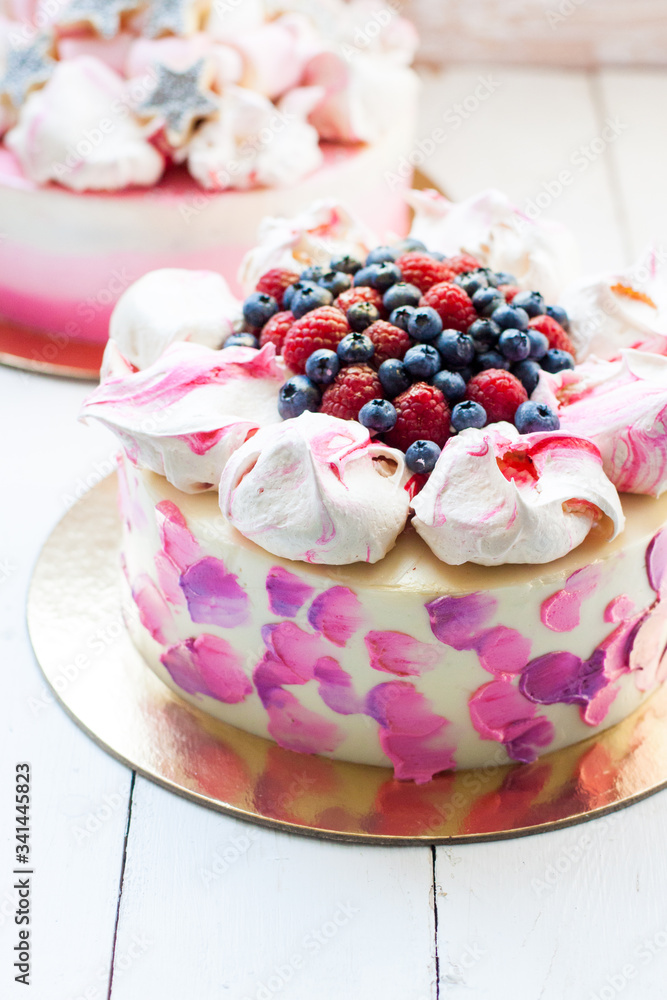 White and pink birhday cake with meringues and fresh berries, raspberries, strawberries and blueberries. White and pink birhday cake with meringues and fresh berries, raspberries, strawberries and blueberries.