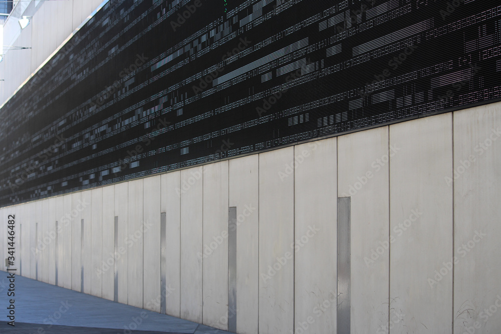 Fototapeta premium Commercial building with a large outdoor digital wall display LED screen with numerals, characters and glitches running across the screen. Sound speakers