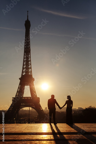 Silhouette of the newlyweds on the background of the Eiffel Tower. The couple is holding hands and looking at each other. Dawn in Paris.