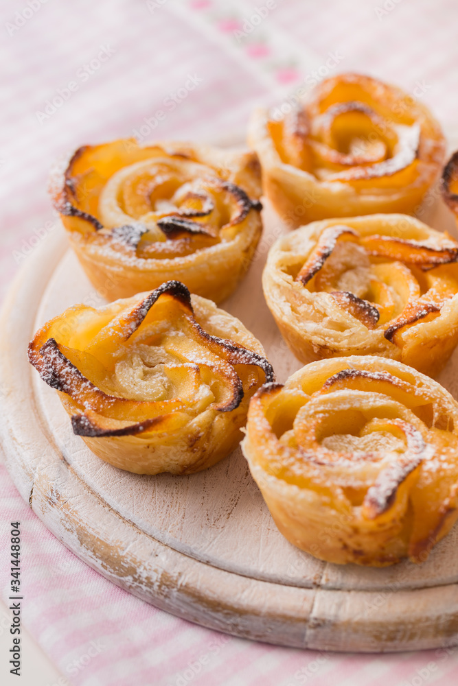 Delicious apple puff pastry in rose shape on wooden board Delicious apple puff pastry in rose shape on wooden board