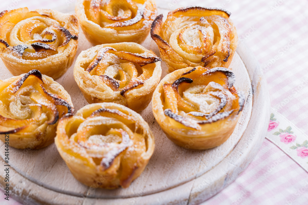 Delicious apple puff pastry in rose shape on wooden board Delicious apple puff pastry in rose shape on wooden board