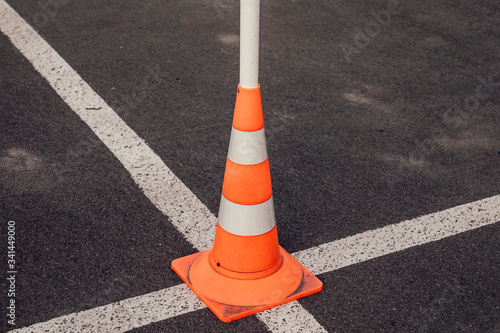 traffic cone at the intersection of the white lines of road markings. Symbol of restrictions, road works, attention. For publications on driving schools, traffic, and road construction